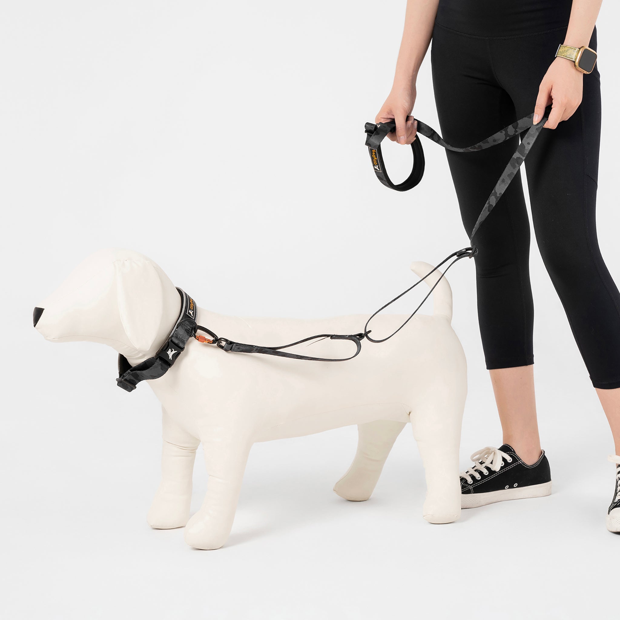 Person holding the OllyDog Flagstaff Adjustable Leash in Dream Camo, clipped to a dog mannequin. The leash features a padded handle, adjustable waist belt, durable polyester webbing, and swivel carabiner, ideal for hands-free and secure dog walking #color_dream camo