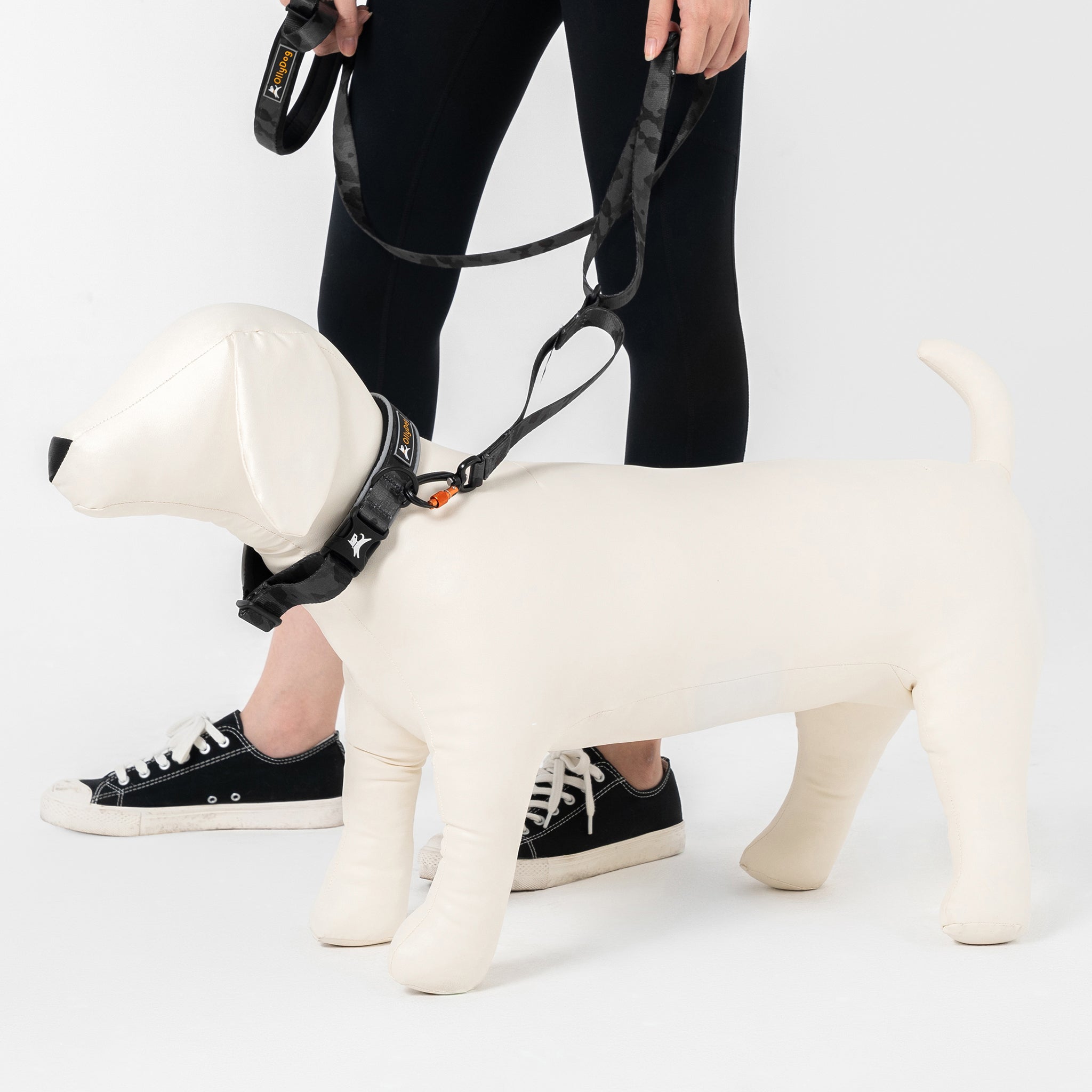 Person holding OllyDog Flagstaff Reflective Comfort Collar and matching leash in dream camo color on dog mannequin, showcasing padded neoprene lining, sublimation polyester webbing, quick-release buckle, and reflective piping for safety and comfortable dog walking #color_dream camo