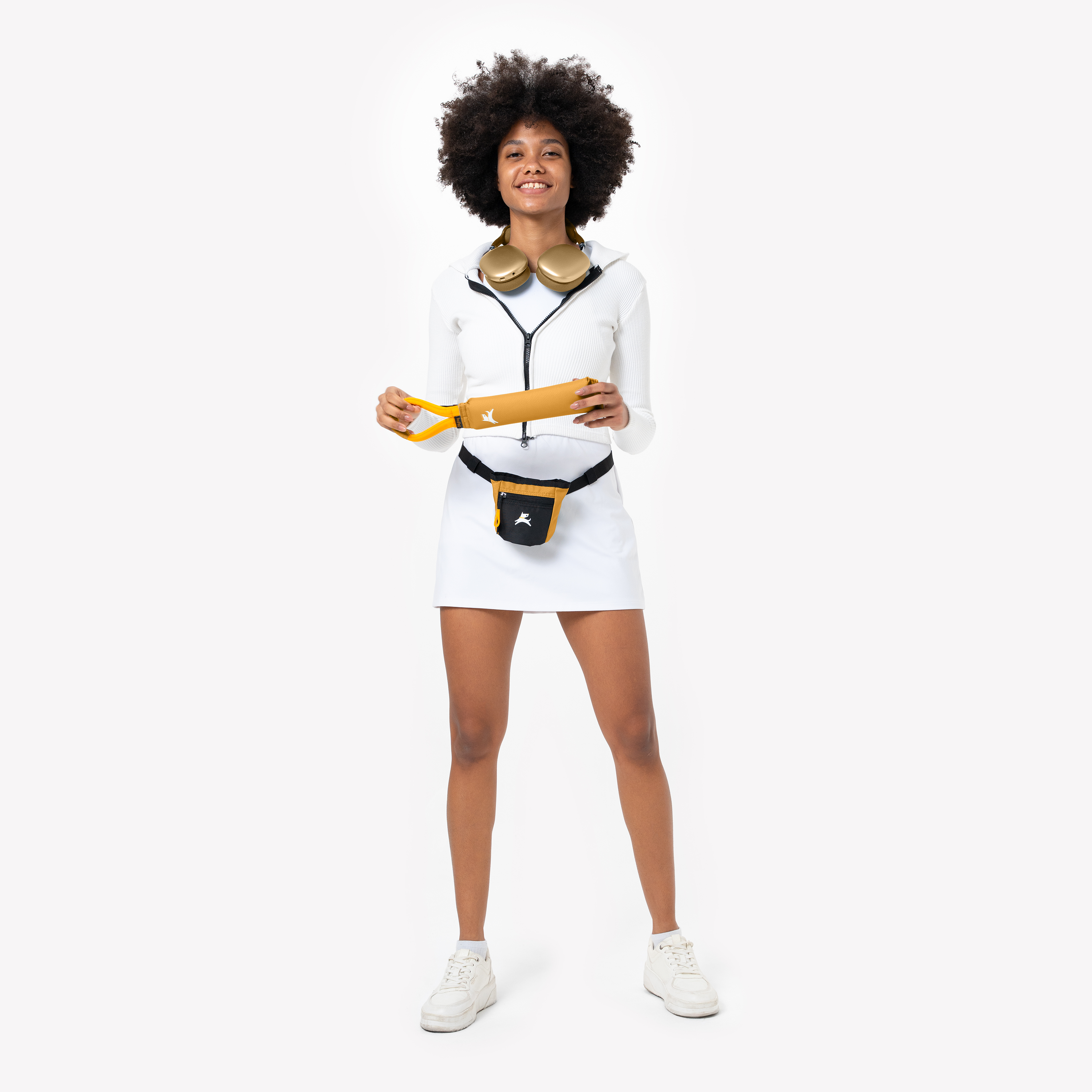 Smiling woman holding mustard yellow dog leash, wearing treat pouch and white activewear for dog walking #color_sundial