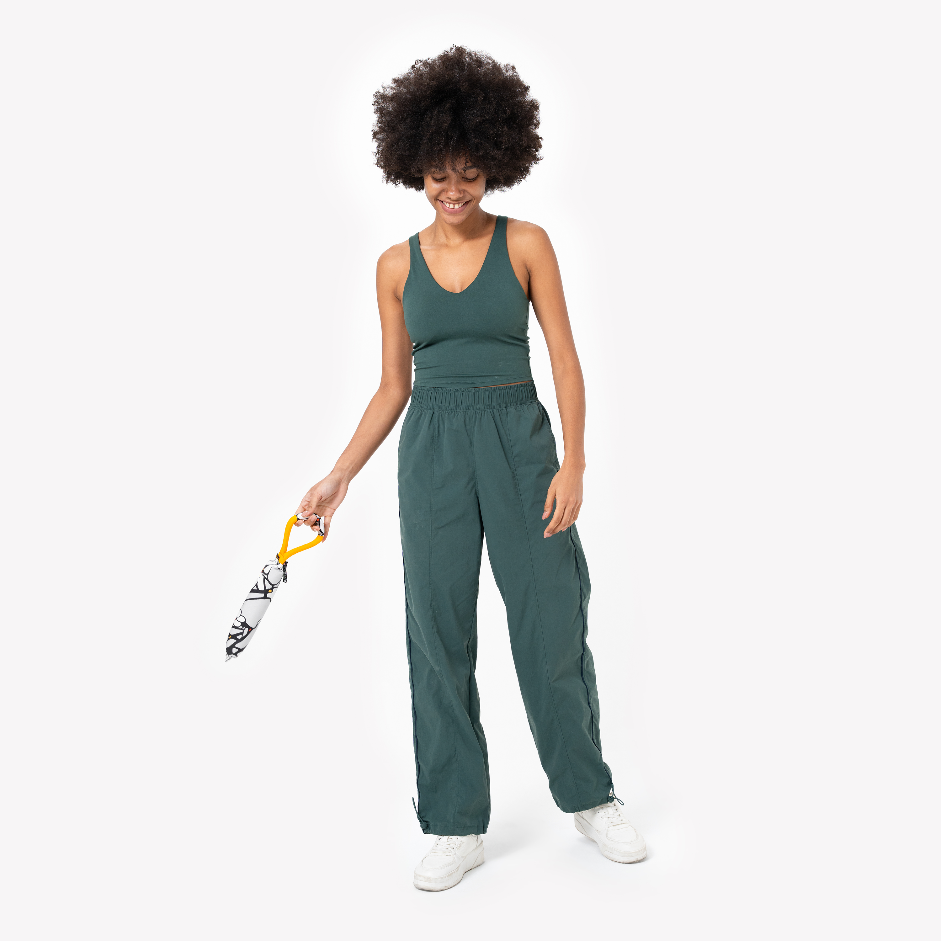 Model smiling while holding the OllyDog Tugger dog toy in Magnolia print, showcasing its floral pattern and sturdy yellow handle, ready for interactive play #color_magnolia