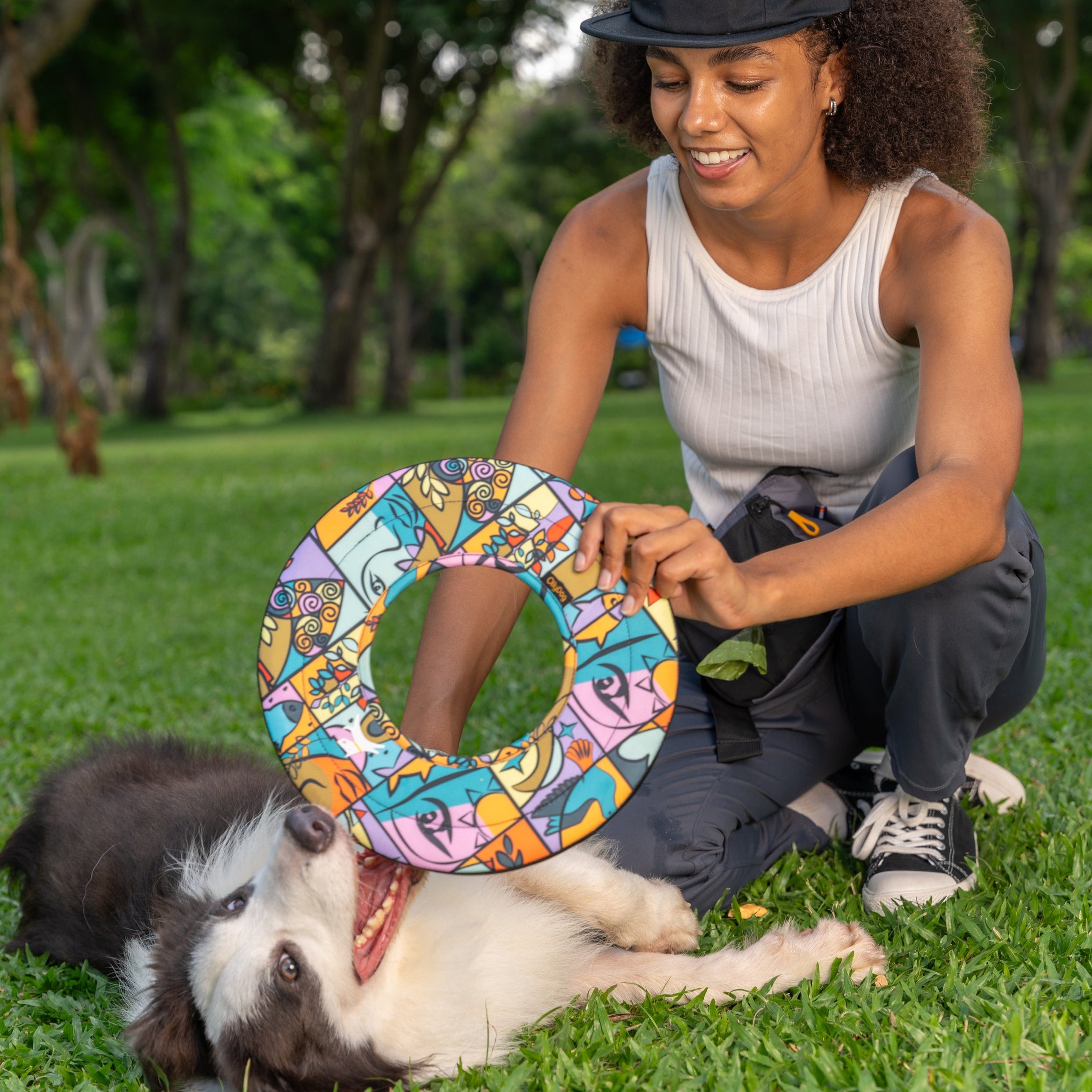 Woman kneeling in park playing with her dog using the OllyDog Super Flyer in Cloud9 pattern, featuring a vibrant abstract design #color_cloud9