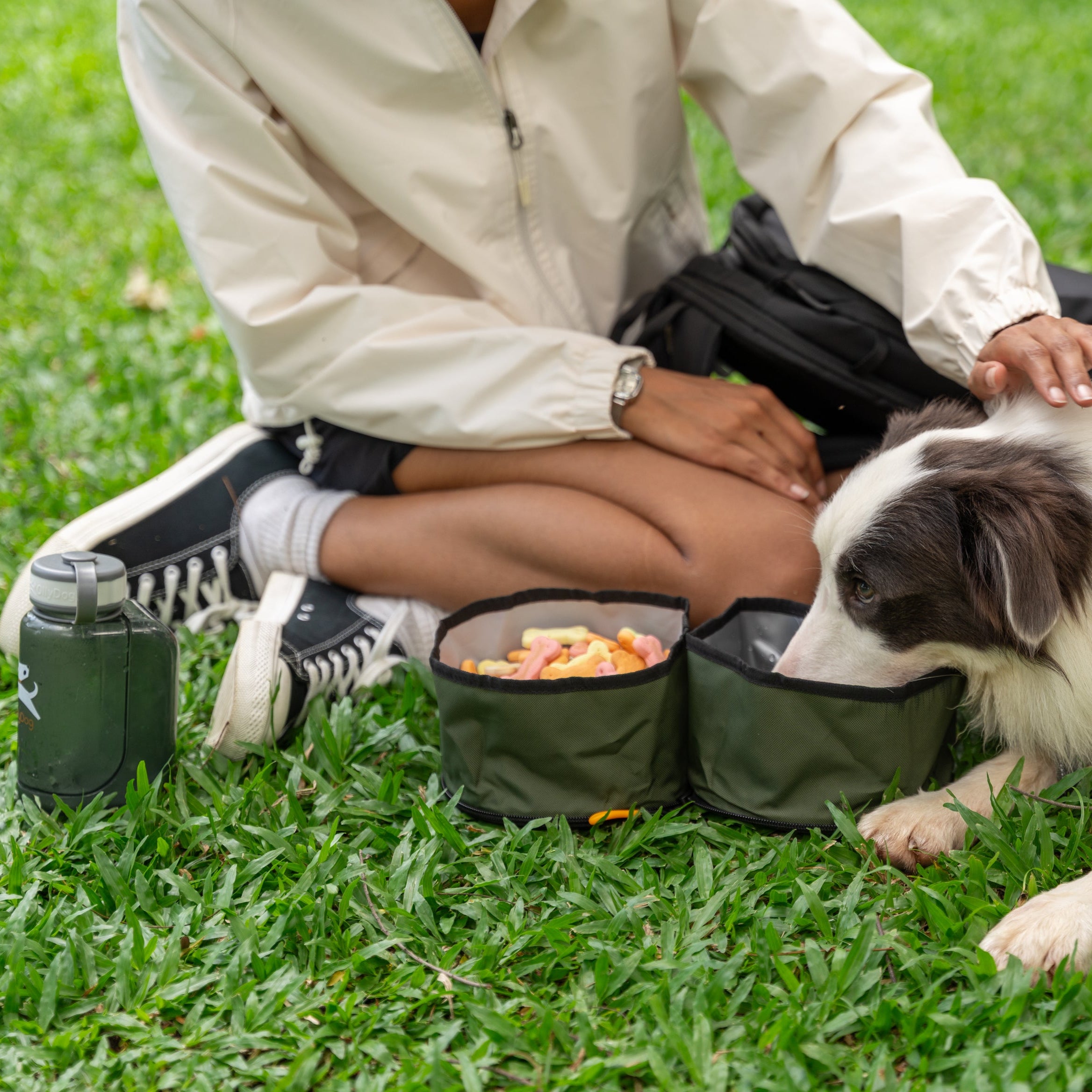 Dog eating and drinking from the OllyDog Superbowl in Winter Moss color while resting beside its owner in the park, with dual bowls for food and water #color_winter moss