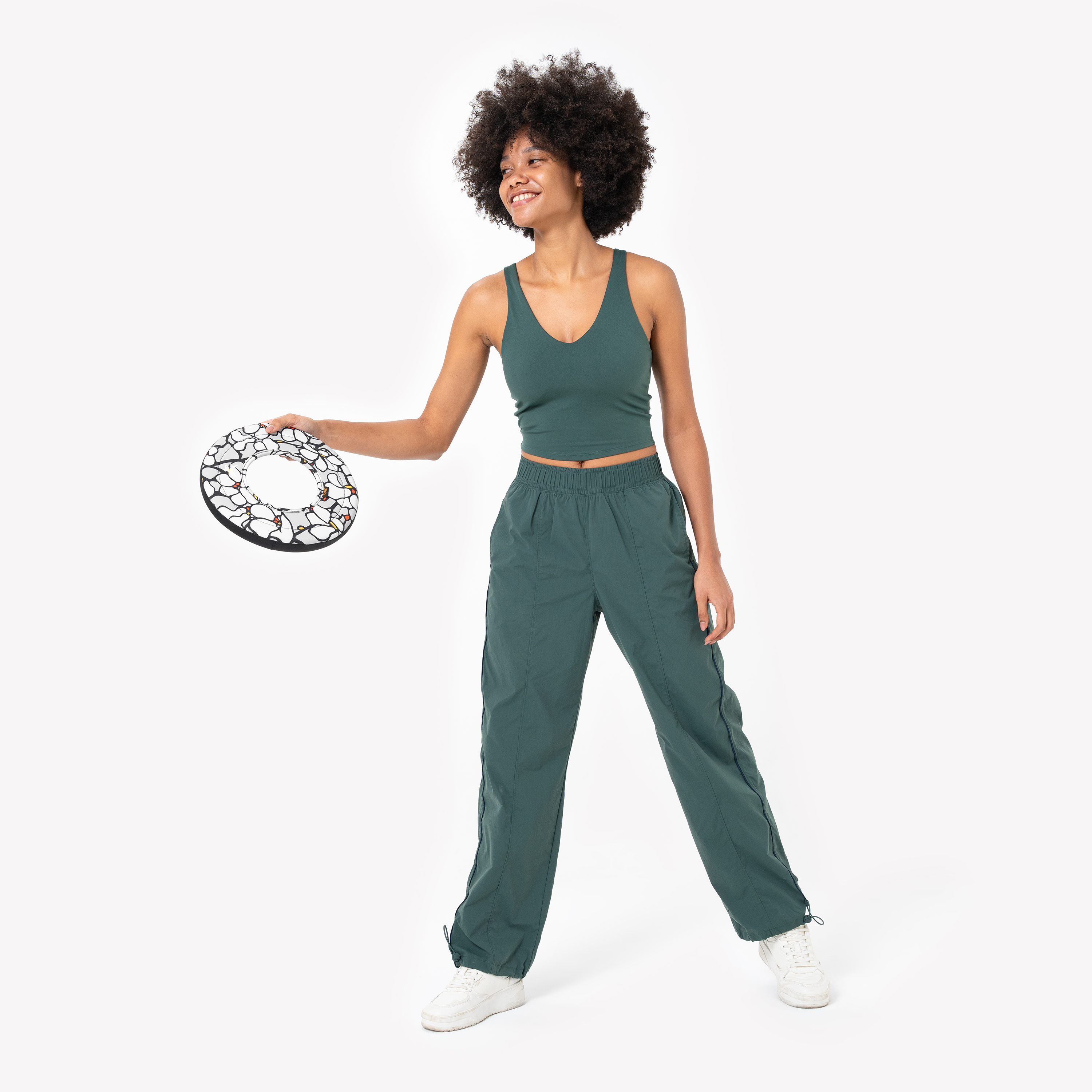 Woman in green activewear smiling while holding a Magnolia Super Flyer fabric dog frisbee with white floral print and black trim #color_magnolia