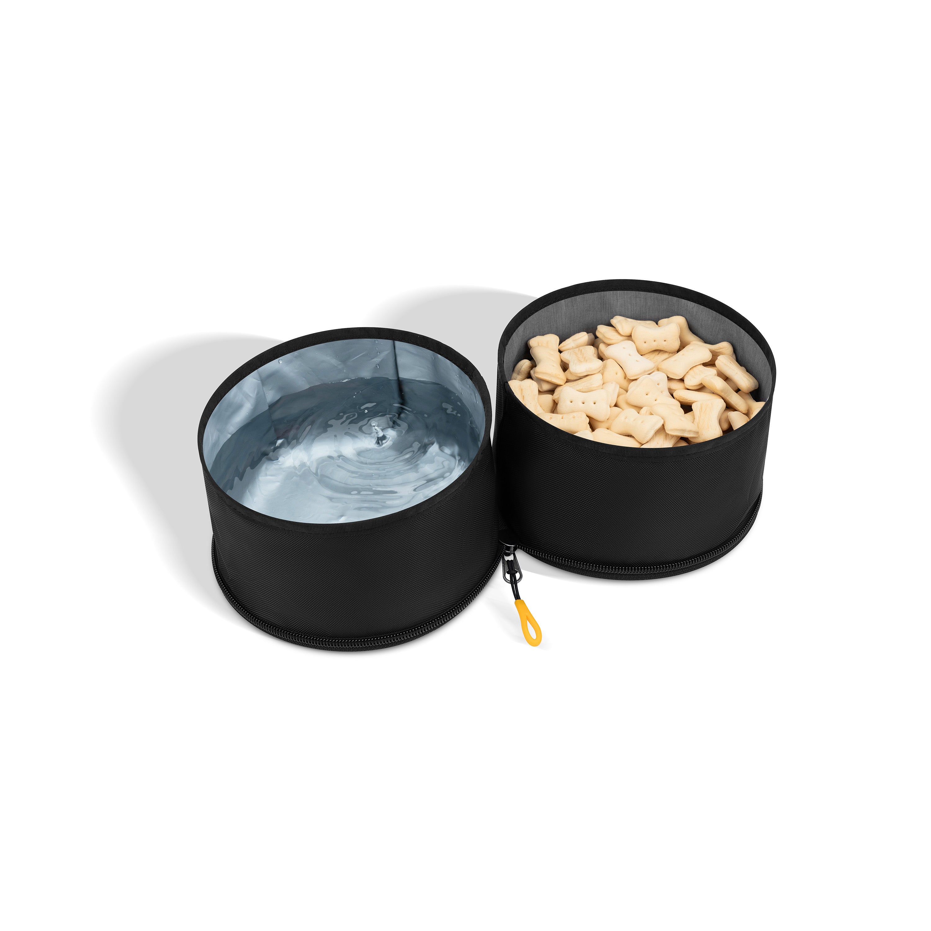 Collapsible dog bowl made of black fabric with two compartments. One compartment is filled with water, and the other contains light-colored kibble. A yellow loop for attachment is visible #color_raven