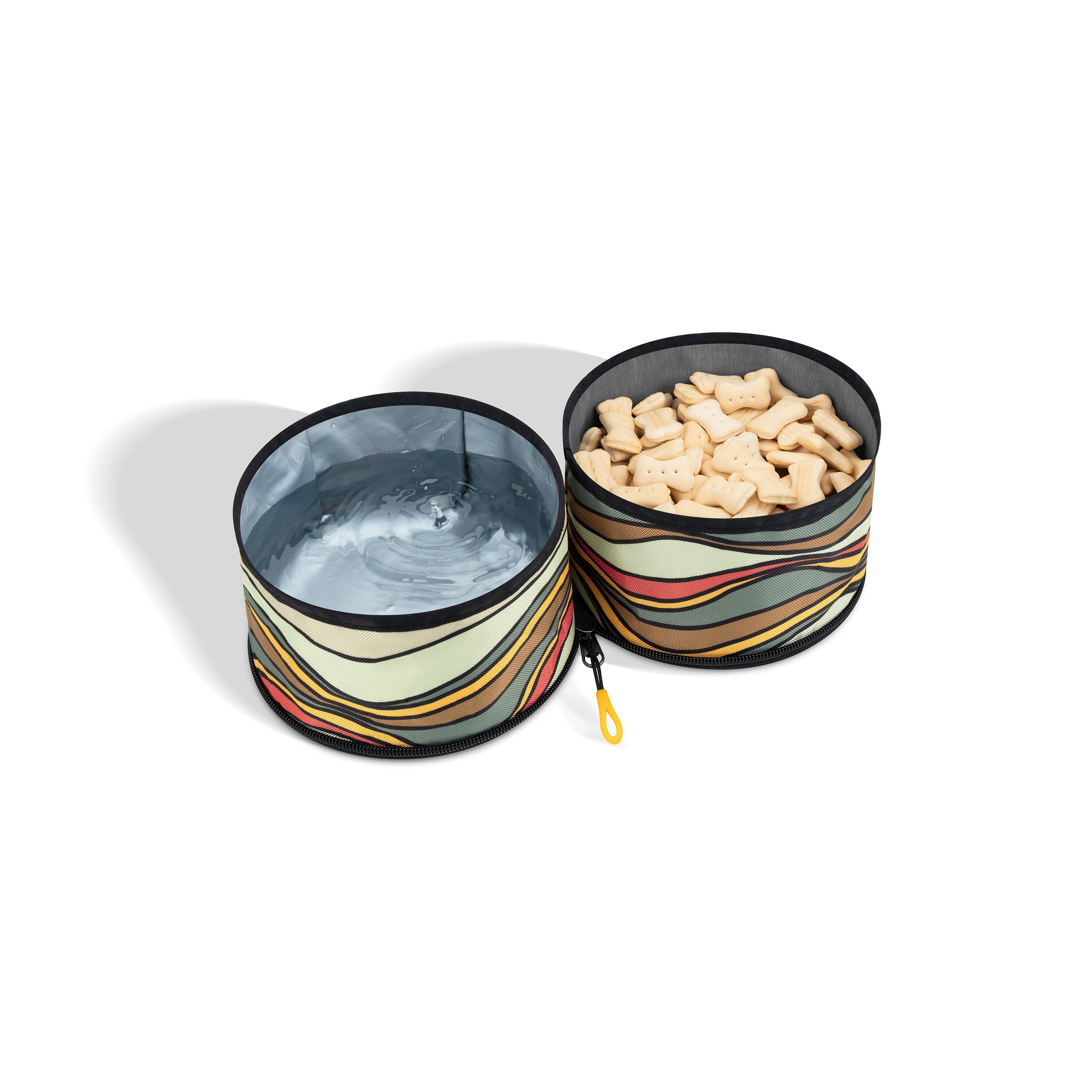 The OllyDog Superbowl in the Ventura '73 pattern features two connected collapsible bowls. One bowl is filled with water, and the other contains light-colored kibble. The bowls have a distinctive retro horizontal stripe design in shades of brown, cream, yellow, and black. A yellow attachment loop is visible #color_ventura '73