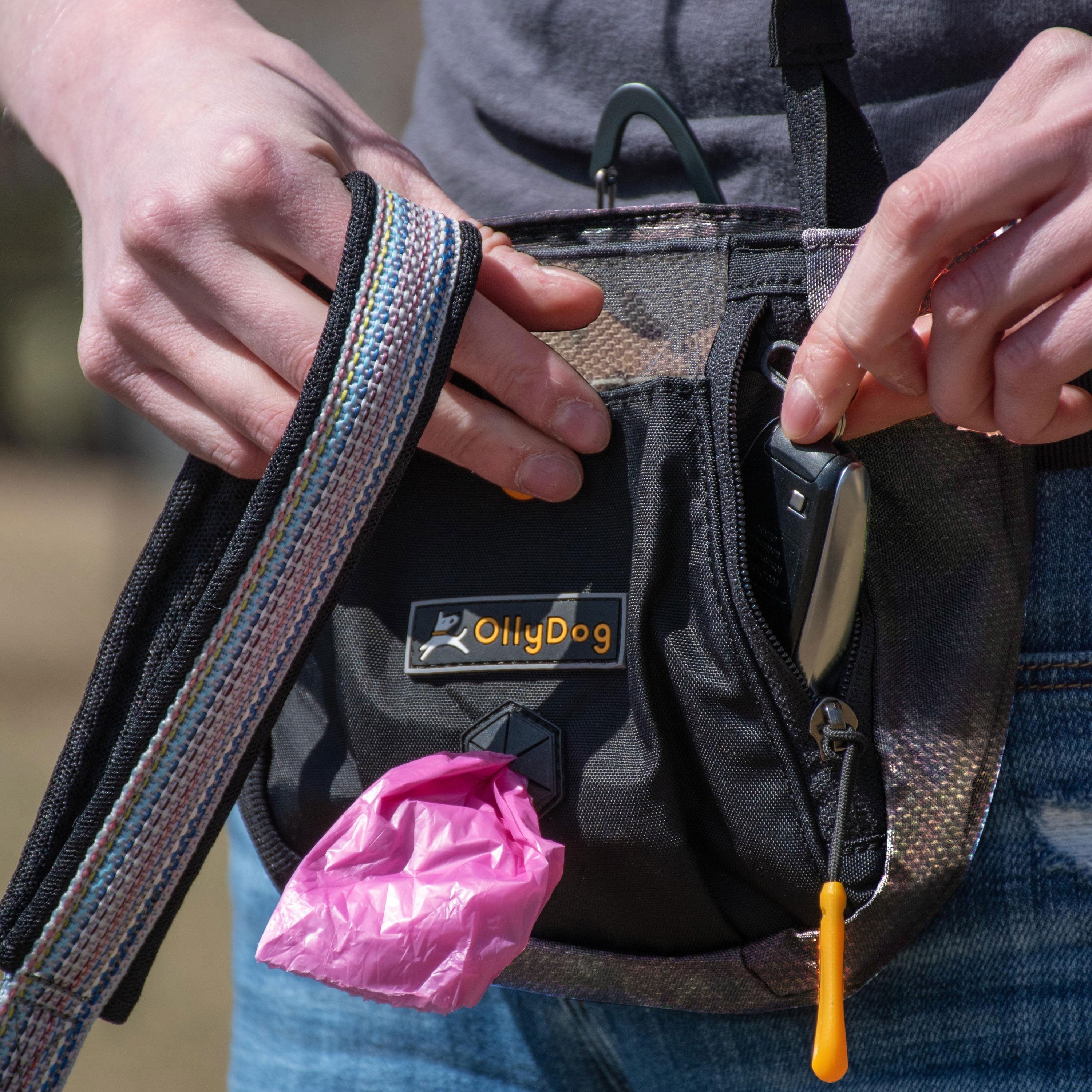 A person in jeans wearing OllyDog’s Backcountry Day Bag in Forest Camo, a dog walking waist pack perfect for hiking with dogs. This essential piece of dog hiking gear is designed for comfort and functionality on dog friendly trails. #color_forest camo