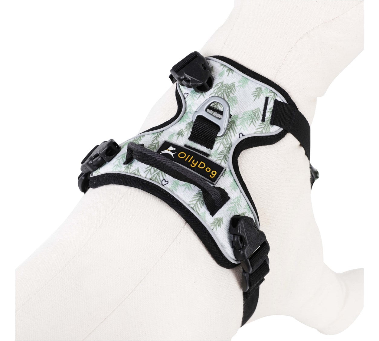Top-angle close-up view of the OllyDog Alpine Reflective Harness in tree hugger print on a mannequin, showcasing the back leash attachment point, brand logo label, handle, and adjustable plastic buckle points. #color_tree hugger print
