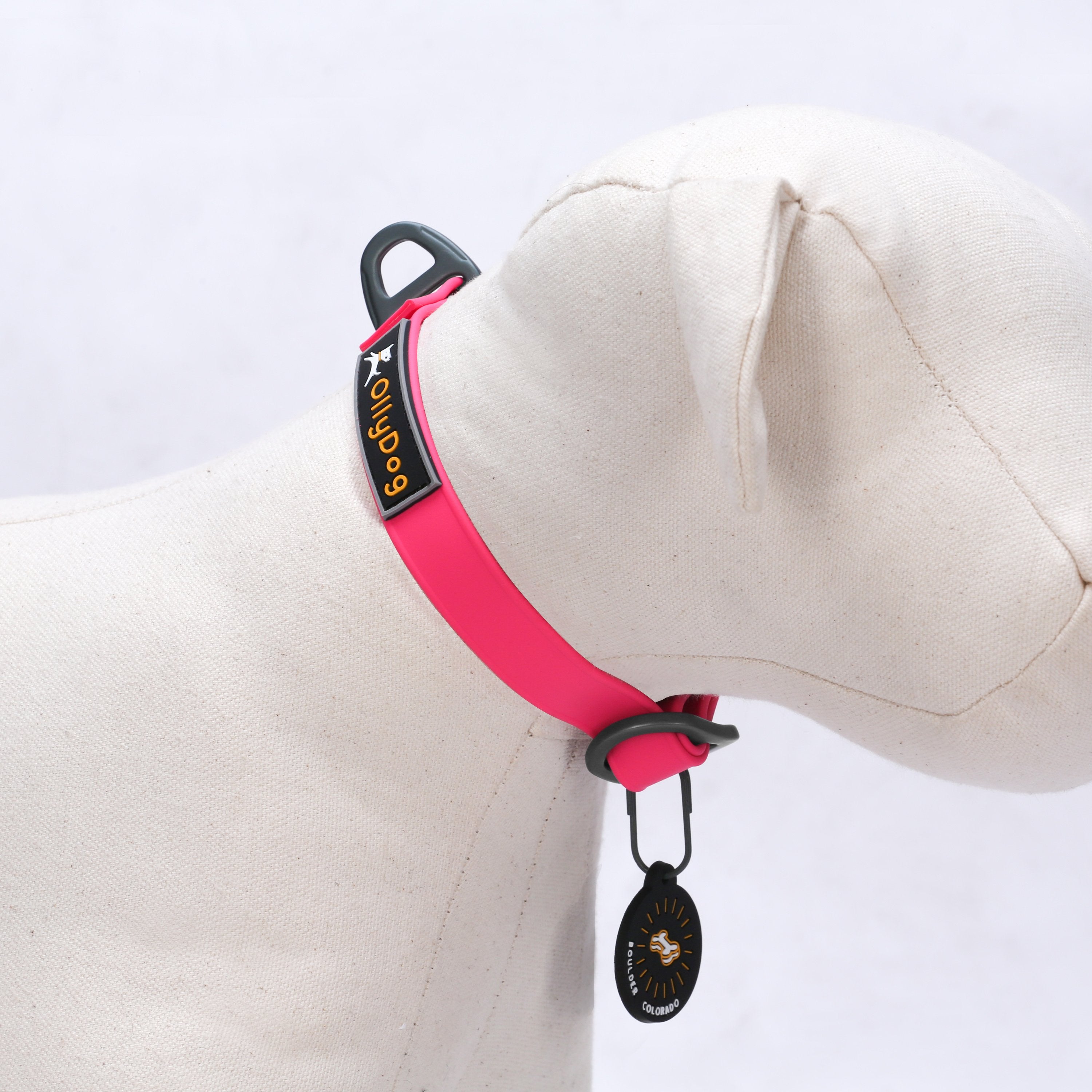 Studio display on a dog mannequin of the OllyDog Tilden Waterproof Collar in pink color, featuring waterproof AquaGuard coating, the OllyDog logo patch, a secure aluminum D-ring, and an attached Boulder Colorado tag. #color_pink