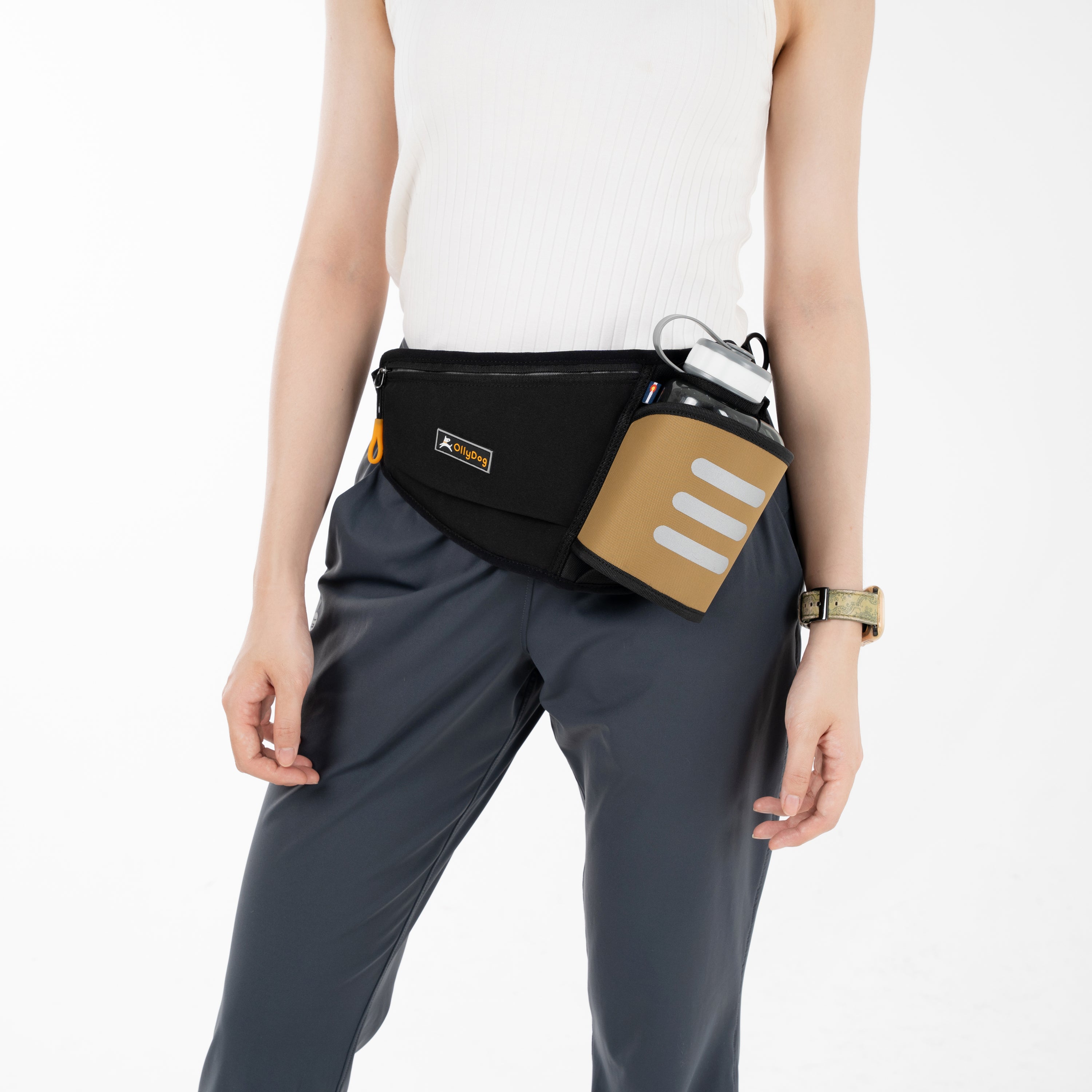 A compact black OllyDog Hydro-Slim Pack with a tan side pocket. The bag has an adjustable black strap and is designed for hands-free walking or running #color_elmwood