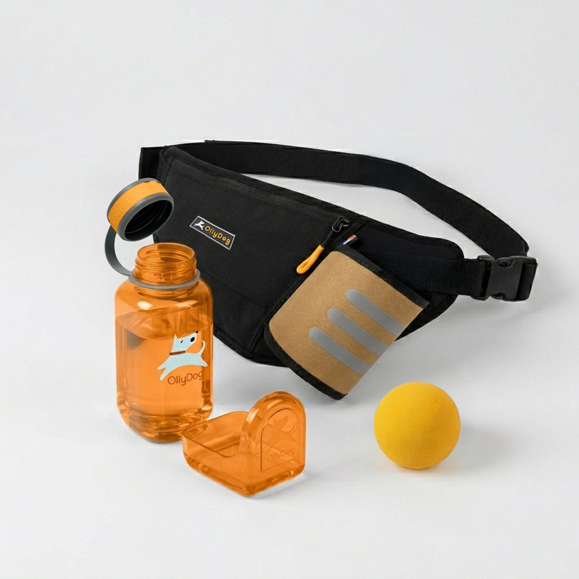 OllyDog dog walking bundle featuring a Raven black Hydro-Slim fanny pack with a tan accent pocket, an orange OllyBottle portable dog water bottle with a detachable drinking bowl, and a yellow rubber Happy Camper ball