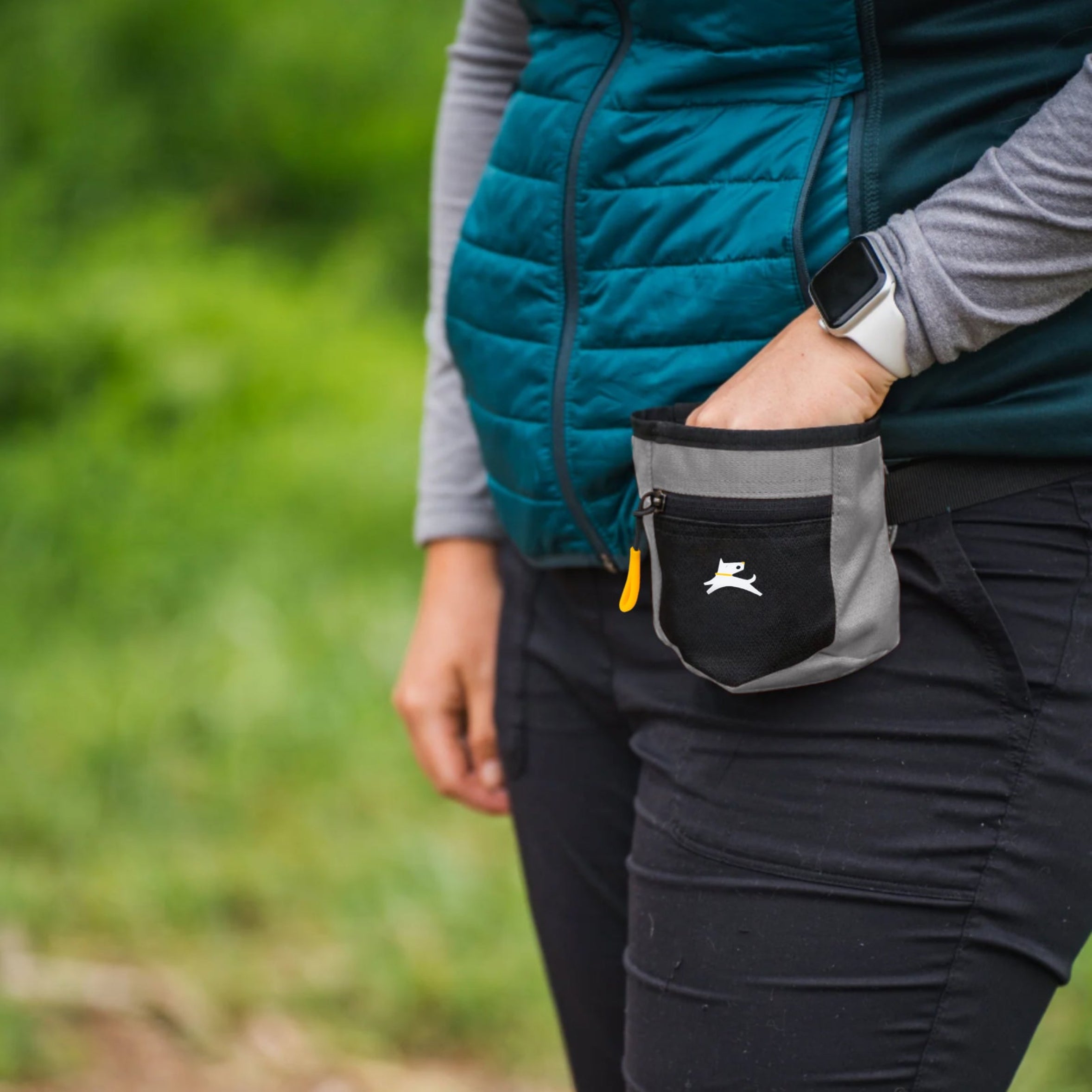 Close-up of a person wearing the water-resistant OllyDog Goodie Treat Bag in wet weather color around their waist and reaching inside for a dog training treat. #color_wet weather
