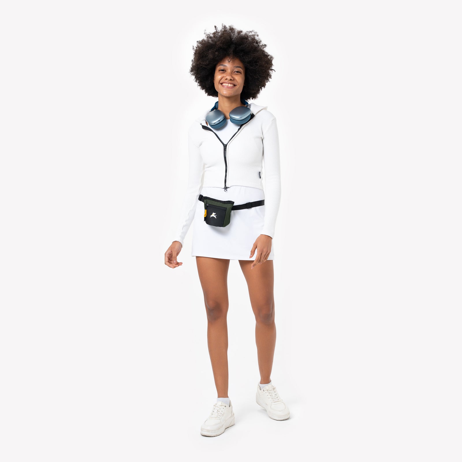 Studio portrait of a smiling model wearing the OllyDog Goodie Treat Bag in winter moss color around her waist against a white background. #color_winter moss