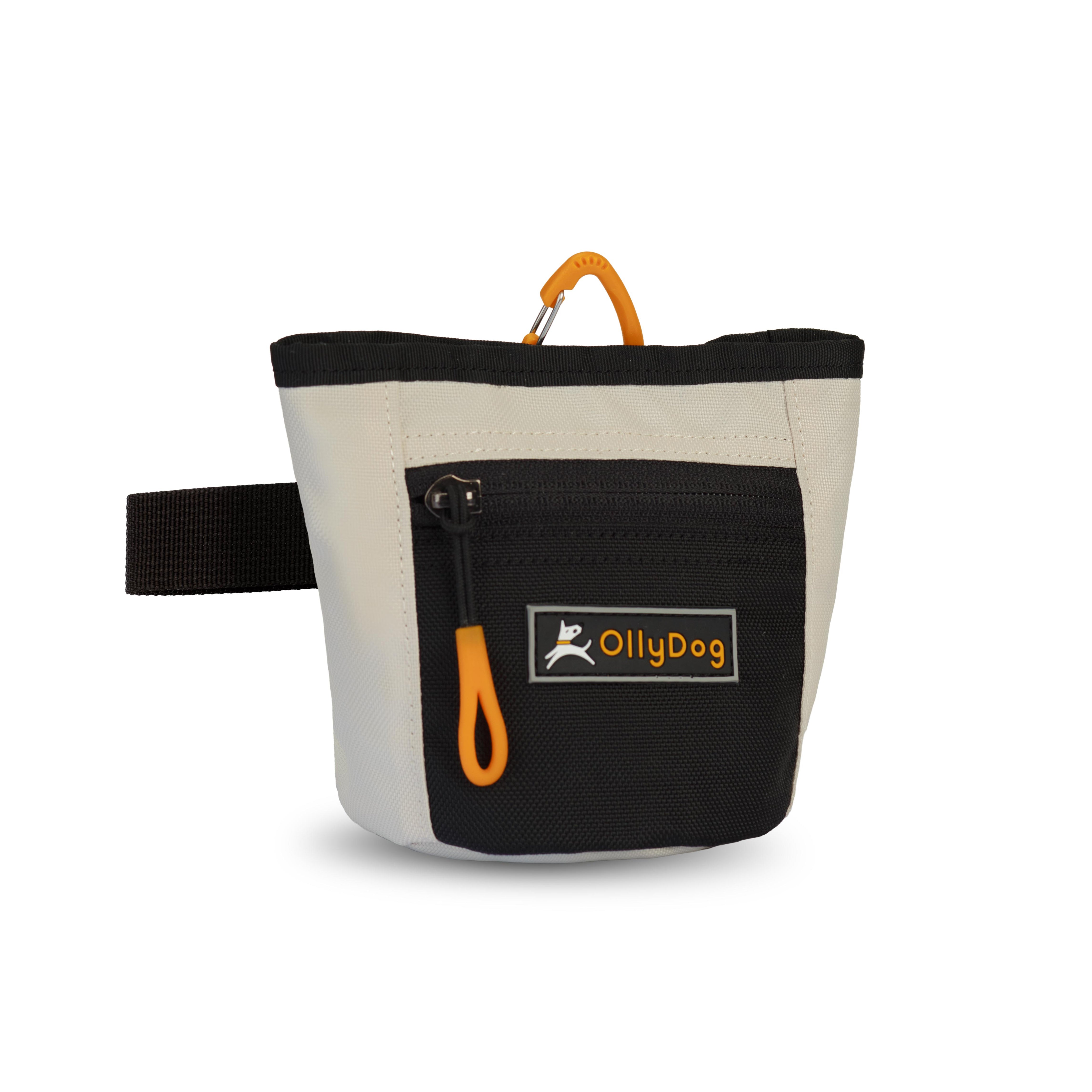 Angled front view of OllyDog’s Goodie Treat Bag in Bluff. The dog treat pouch includes a magnetic closure on the main compartment, a front zipper pocket, and an adjustable waist strap for hands-free dog training. #color_bluff